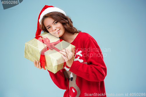 Image of Girl dressed in santa hat with a Christmas gift