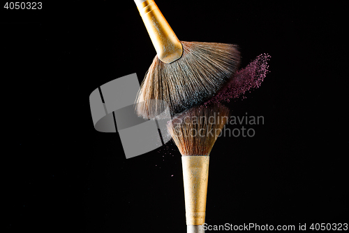 Image of Make-up brushes with pink powder isolated on black background