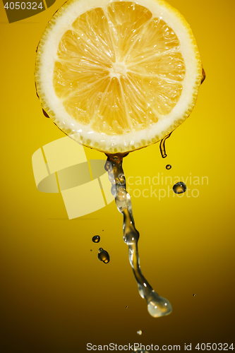 Image of Lemon slice and splash of juice isolated on orange background