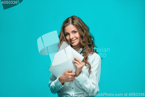 Image of The smiling young business woman with pen and tablet for notes on blue background