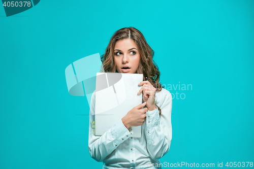 Image of The thoughtful young business woman with pen and tablet for notes on blue background