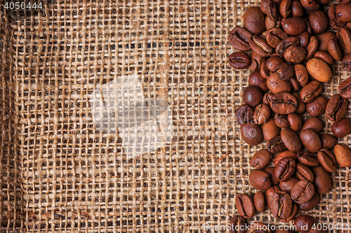 Image of Black coffee beans in burlap sack on wooden table,