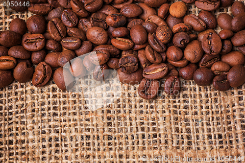 Image of Black coffee beans in burlap sack on wooden table,