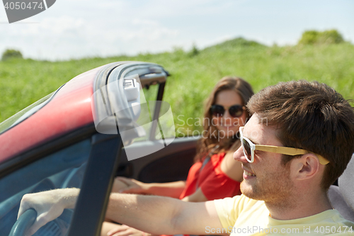 Image of happy couple driving in cabriolet car at country