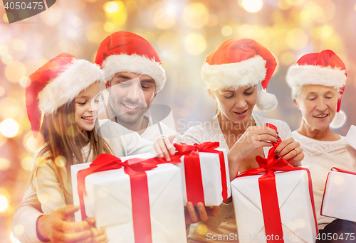 Image of happy family in santa hats with gift boxes