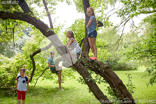 Image of happy kids climbing up tree in summer park