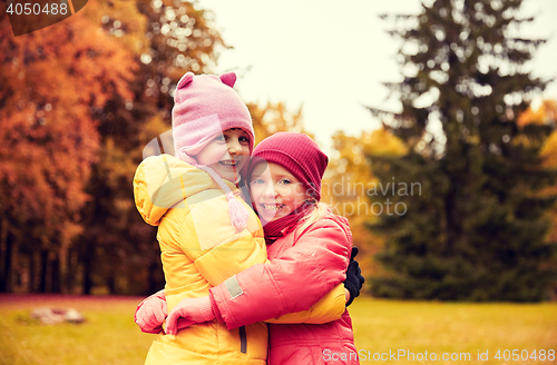 Image of two happy little girls hugging in autumn park