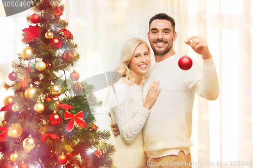 Image of happy couple decorating christmas tree at home