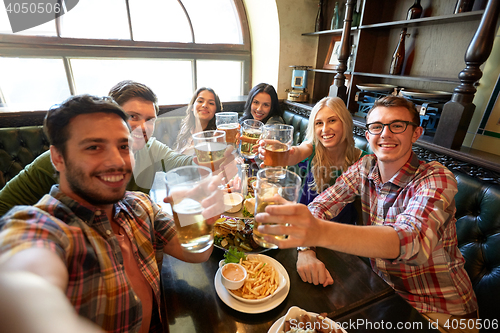 Image of happy friends taking selfie at bar or pub