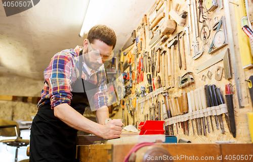 Image of carpenter working with plane and wood at workshop