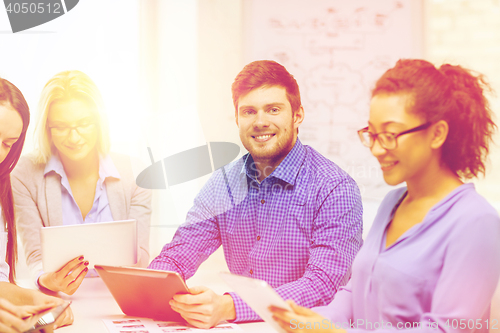 Image of smiling team with table pc and papers working