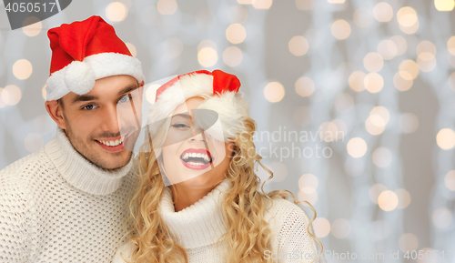 Image of happy family couple in sweaters and santa hats