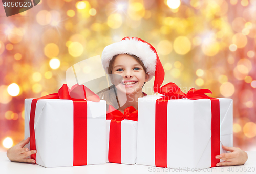 Image of smiling girl in santa hat with christmas gifts