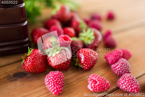 Image of bottle with juice and berries on wooden table