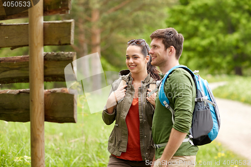 Image of smiling couple at signpost with backpacks hiking