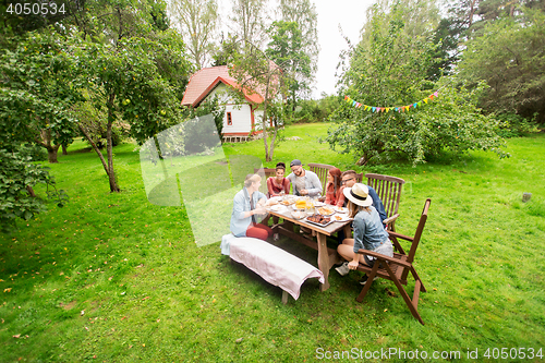 Image of happy friends having dinner at summer garden party