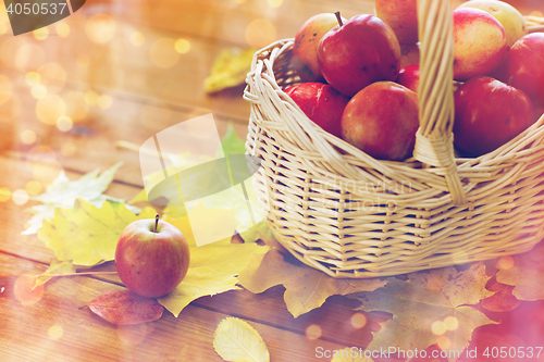 Image of close up of basket with apples on wooden table