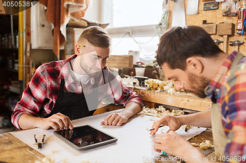 Image of workmen with tablet pc and blueprint at workshop