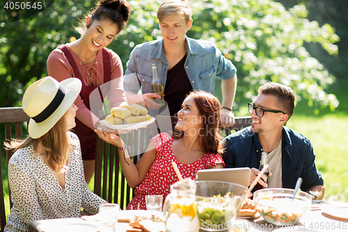 Image of happy friends having dinner at summer garden party