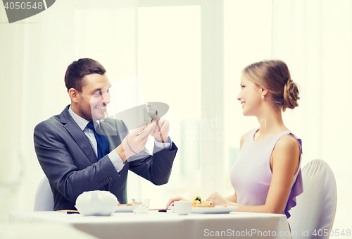 Image of smiling man taking picture with digital camera