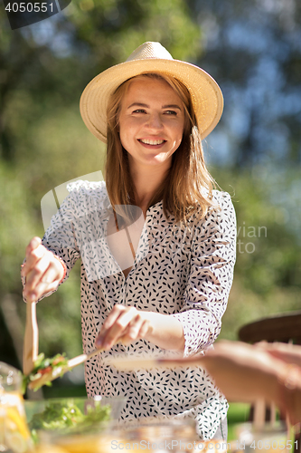 Image of happy young woman serving dinner at summer garden