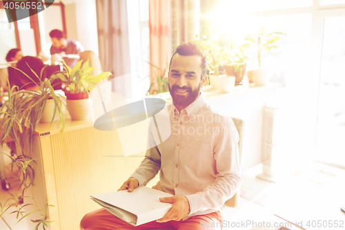 Image of happy creative male office worker with folfer