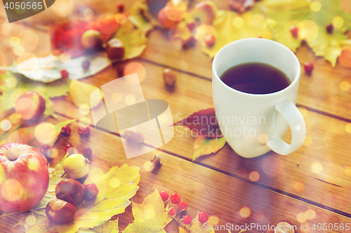 Image of close up of tea cup on table with autumn leaves