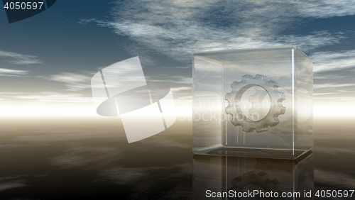 Image of gear wheel in glass cube on reflective surface - 3d rendering