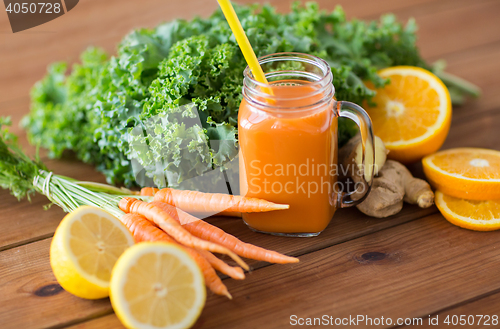 Image of glass jug of carrot juice, fruits and vegetables