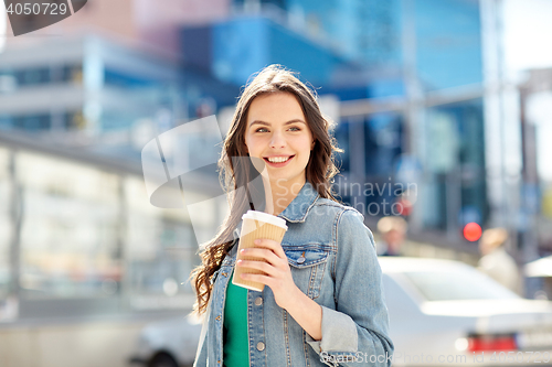 Image of happy young woman drinking coffee on city street