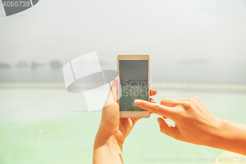 Image of close up of female hand with smartphone on beach