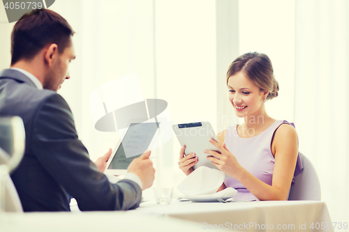 Image of couple with menus on tablet pc at restaurant