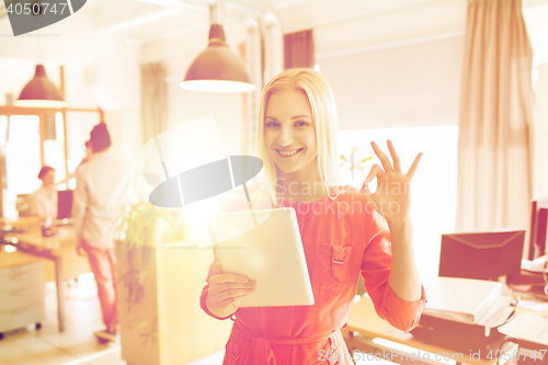 Image of woman with tablet pc showing ok sign at office