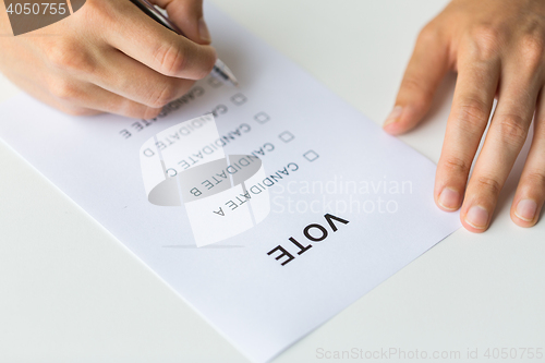 Image of close up of hands with vote or ballot on election