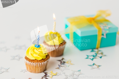 Image of birthday cupcakes with burning candles and present