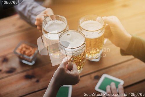 Image of close up of hands with beer mugs at bar or pub