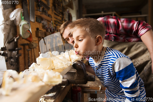 Image of father and little son with wood plank at workshop