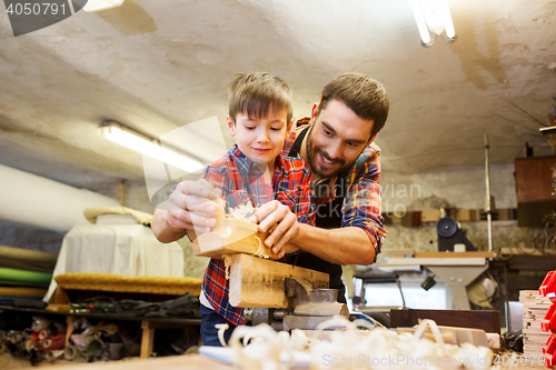Image of father and son with plane shaving wood at workshop