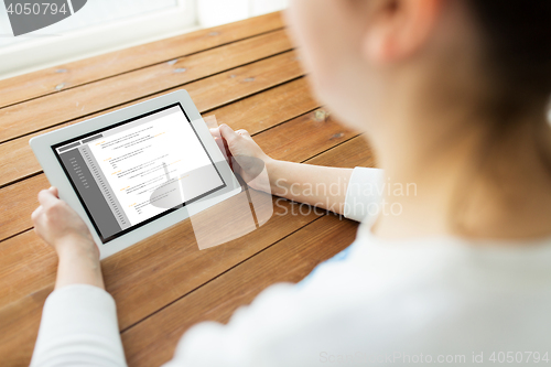 Image of close up of woman with tablet pc on wooden table