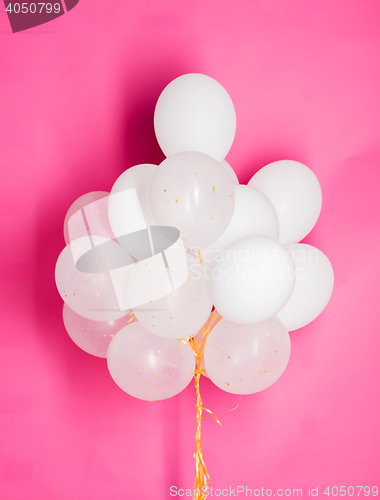 Image of close up of white helium balloons over pink