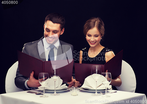 Image of smiling couple with menus at restaurant