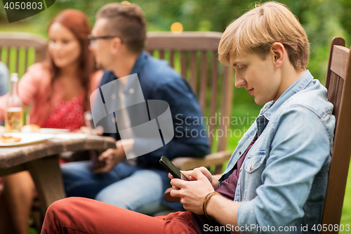 Image of man with smartphone and friends at summer party