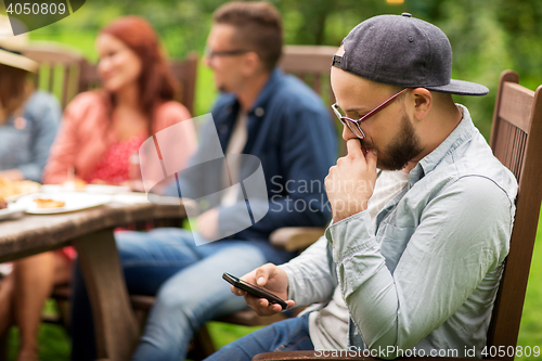 Image of man with smartphone and friends at summer party