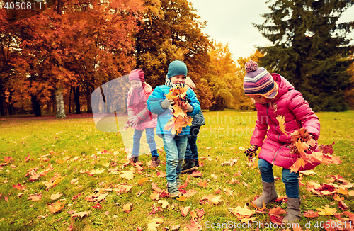 Image of group of children collecting leaves in autumn park