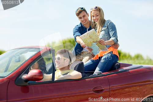 Image of happy friends with map driving in cabriolet car