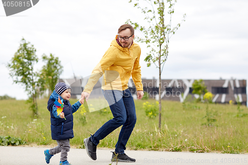 Image of happy father and son with pinwheel toy outdoors