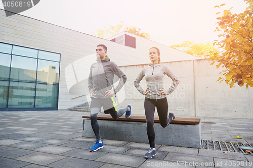 Image of couple doing lunge exercise on city street