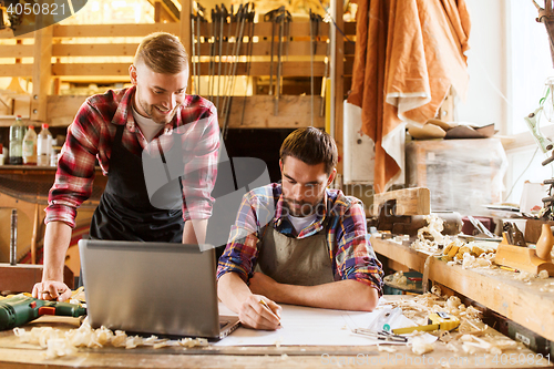 Image of carpenters with laptop and blueprint at workshop