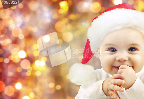 Image of happy baby in santa hat over christmas lights