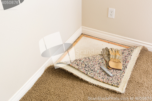 Image of Gloves and Utility Knife On Pulled Back Carpet and Pad In Room.